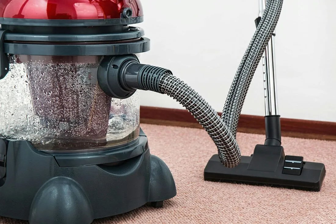 a closeup of a vacuum cleaner being used to clean carpet flooring