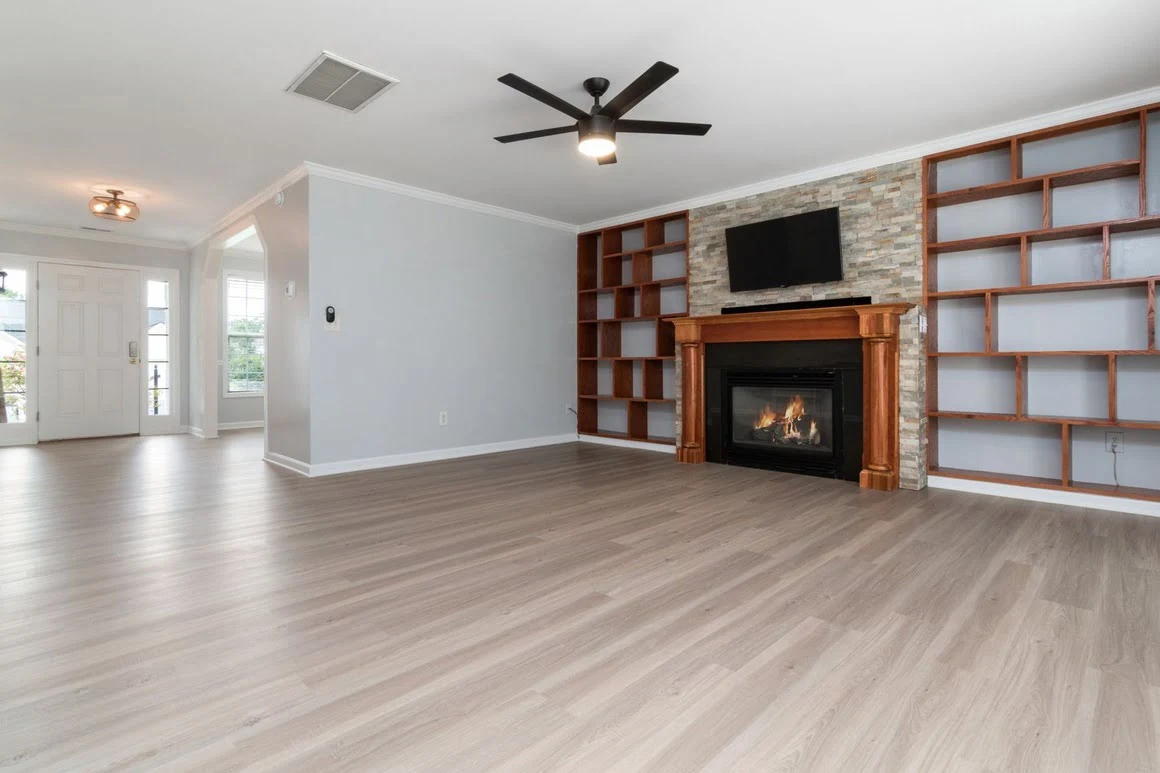 An empty living room and entryway featuring newly installed laminate flooring.