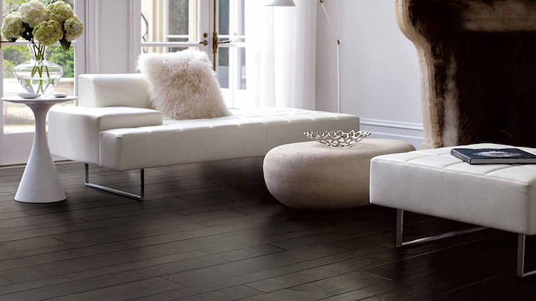 dark stained hardwood flooring in a minimalist living room with a white couch and fireplace